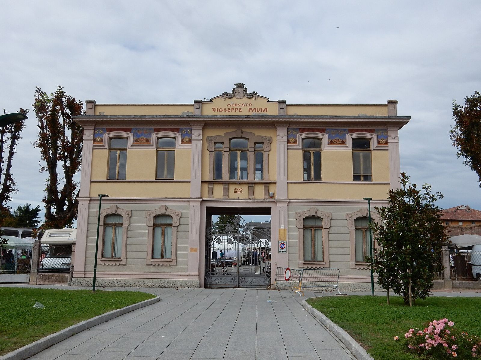 Edificio d'ingresso del Mercato Giuseppe Pavia a Casale Monferrato, con il cancello aperto sui banchi del mercatino