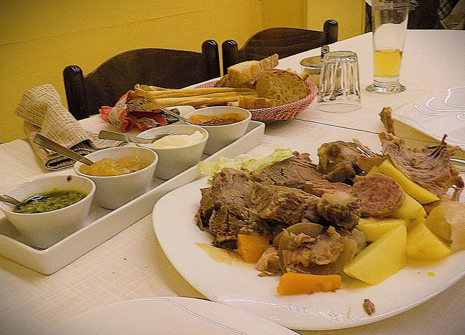 Piatto di bollito misto piemontese con patate e carote, accanto a ciotole di salse fra cui il bagnet verd